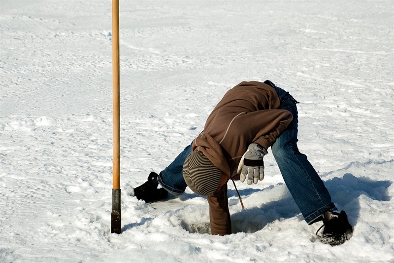 Young man fishing through ice